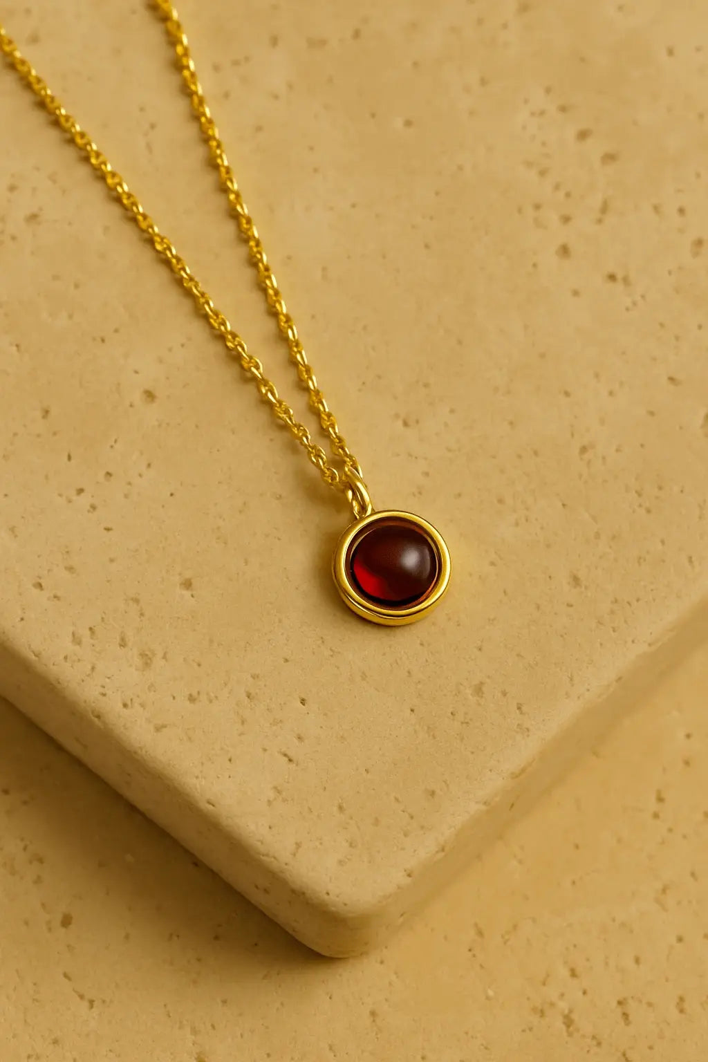 Colar minimalista granada dourado sobre pedra natural clara