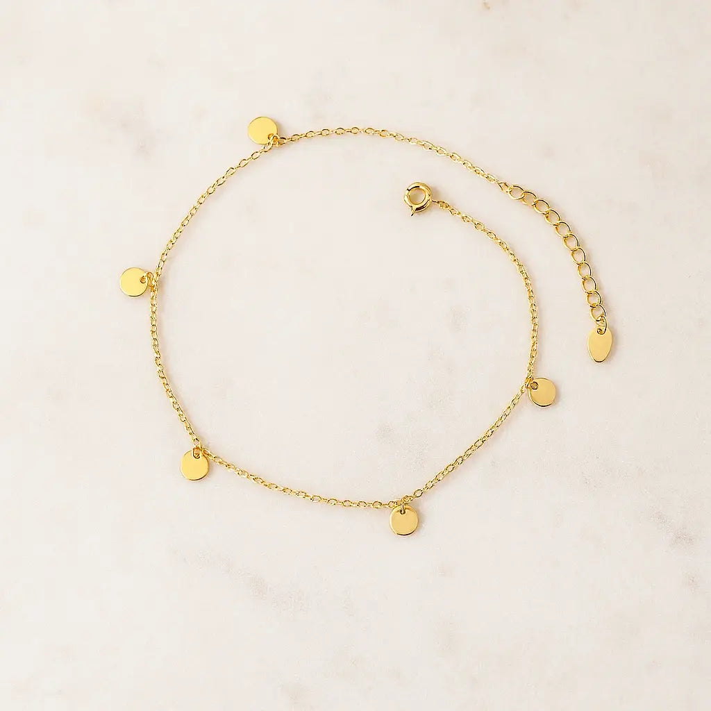 Tornozeleira minimalista elos circulares dourado sobre pedra natural clara