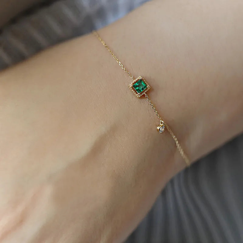 Pulseira dourada delicada em uso, brilho das zircônias verdes - Loja Simplicité