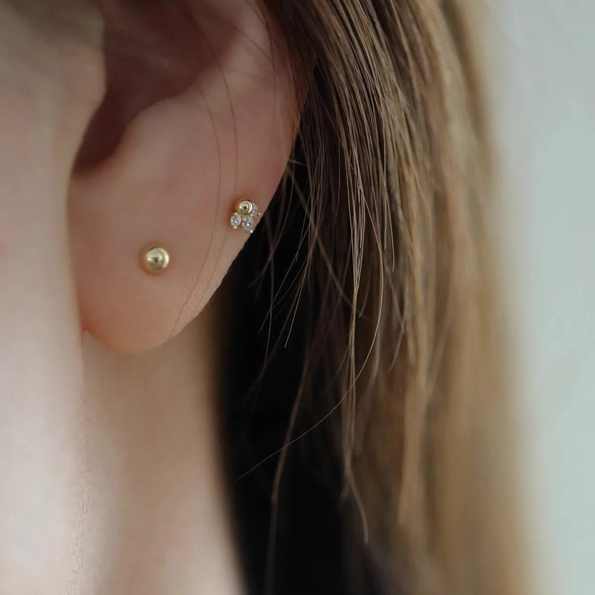 Brincos dourados mini cauda de sereia, banho ouro 14K, em detalhe - Loja Simplicité