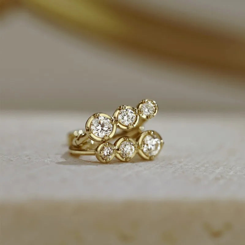 Brinco dourado argola de zircônia em fundo claro - Loja Simplicité