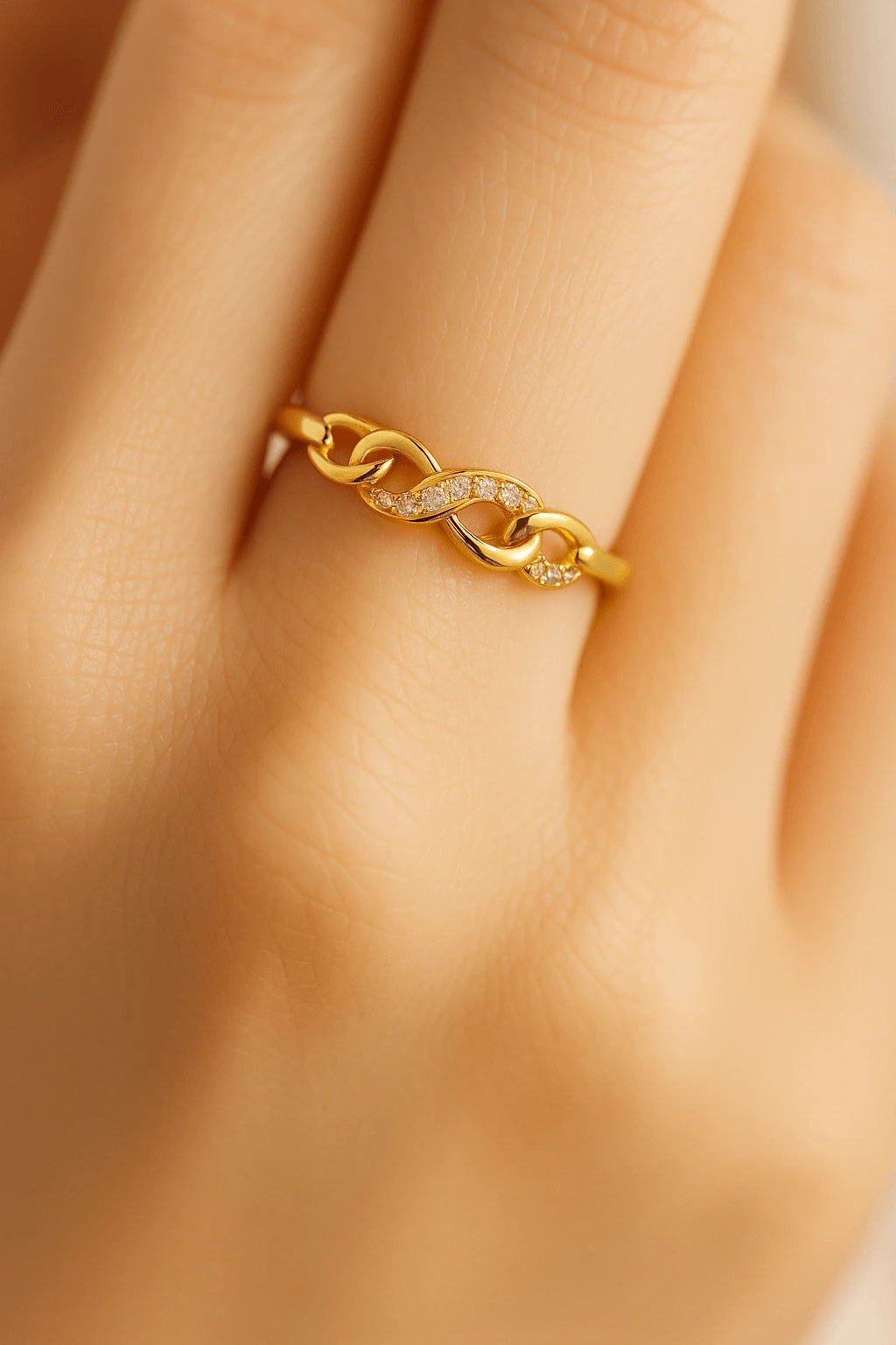 Mão feminina usando anel de infinito dourado com zircônia estilo romântico