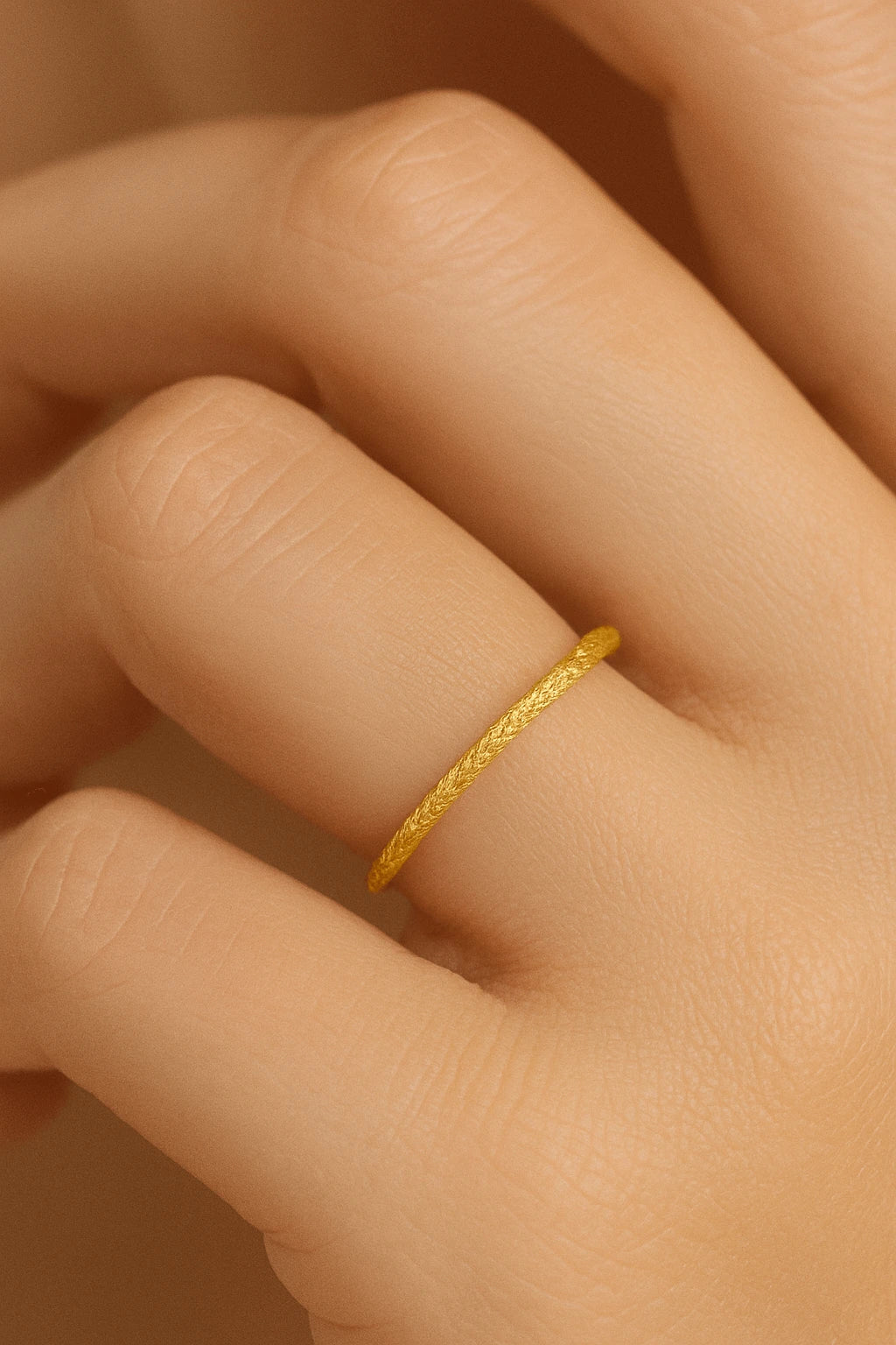 Mão feminina usando anel fininho facetado dourado estilo aparador
