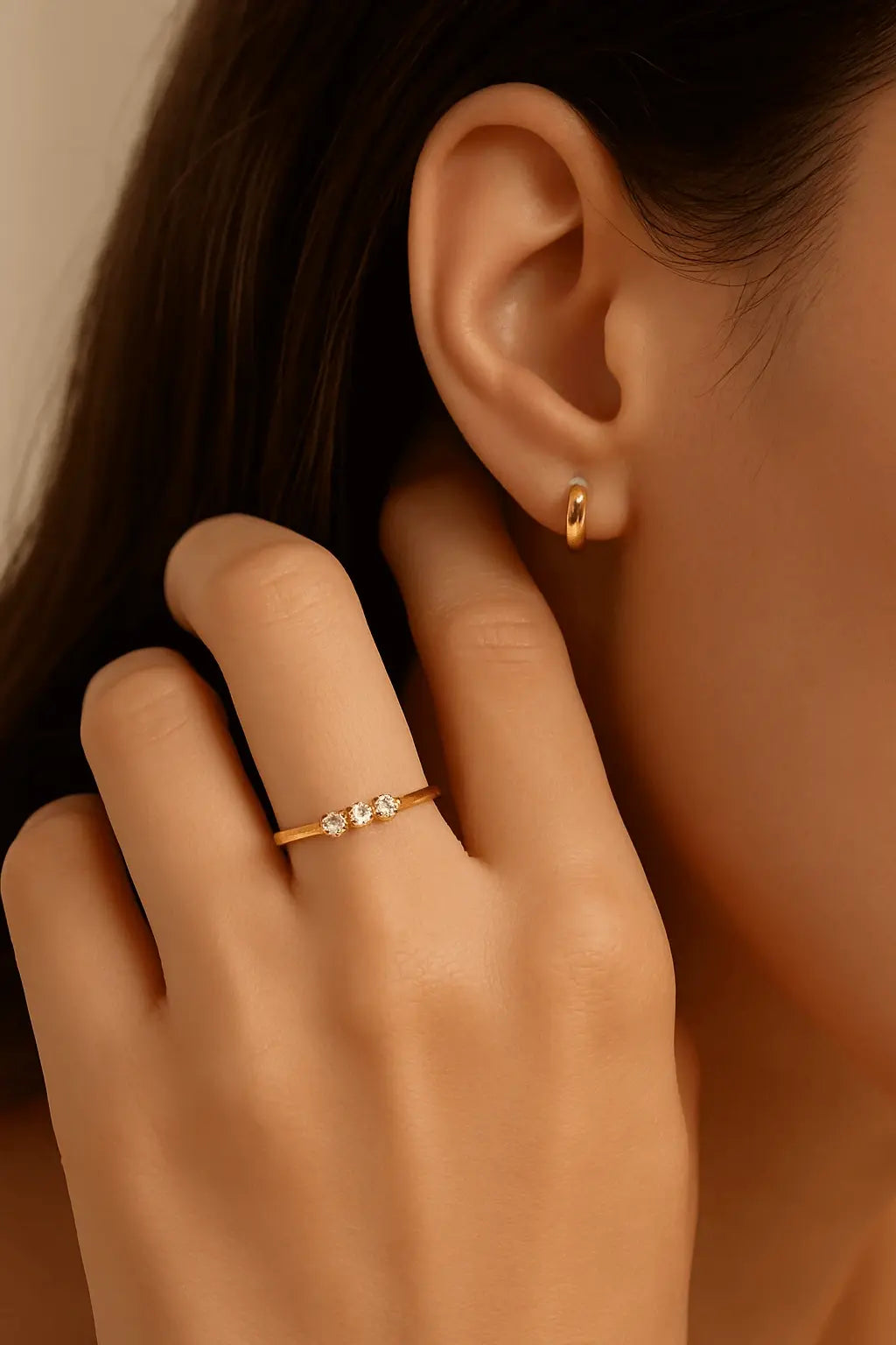 Mão feminina usando anel fininho com três zircônias estilo romântico