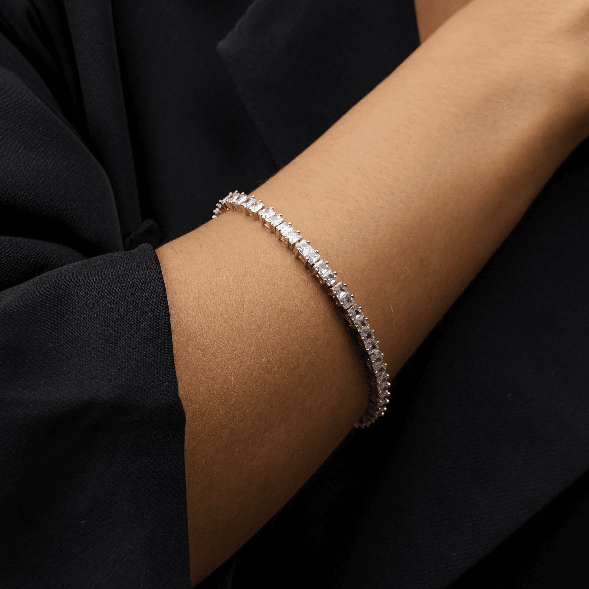 Pulseira riviera dourada com zircônias Rivière Lumineuse no pulso de modelo com blazer preto