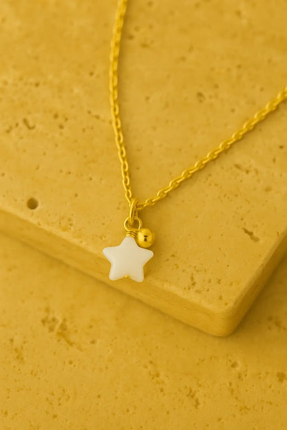 Colar minimalista estrela madrepérola dourado sobre pedra natural clara