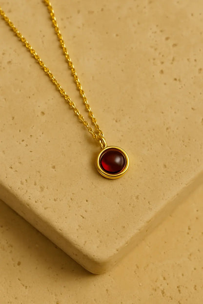 Colar minimalista granada dourado sobre pedra natural clara