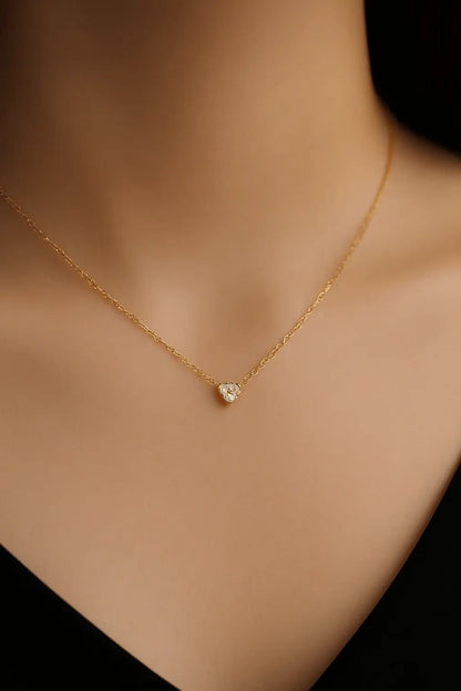 Pescoço feminino usando colar de mini coração dourado estilo sutil e romântico
