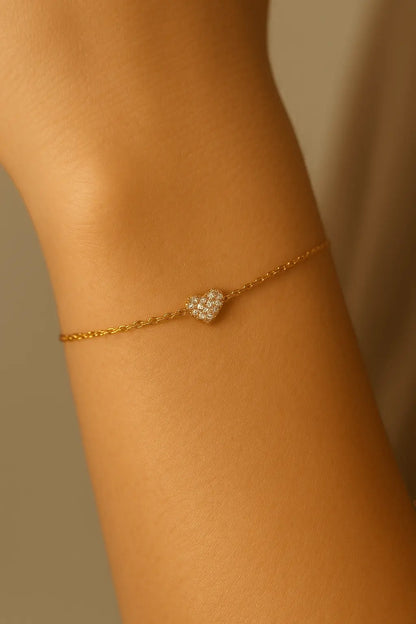 Pulso feminino usando pulseira de coração dourado com zircônias estilo elegante