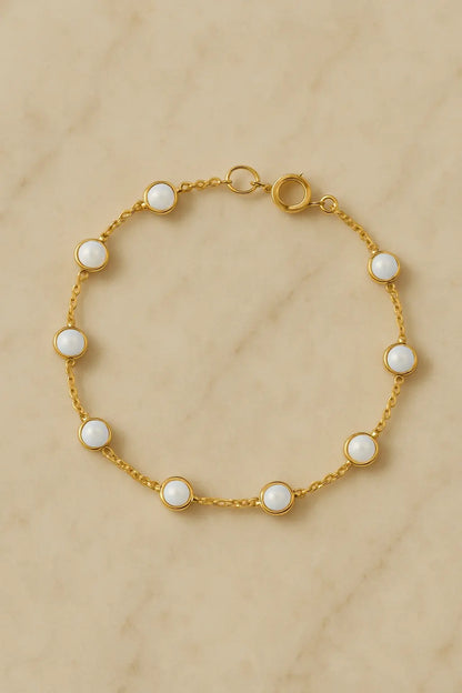 Pulseira minimalista opalina dourada sobre pedra natural clara