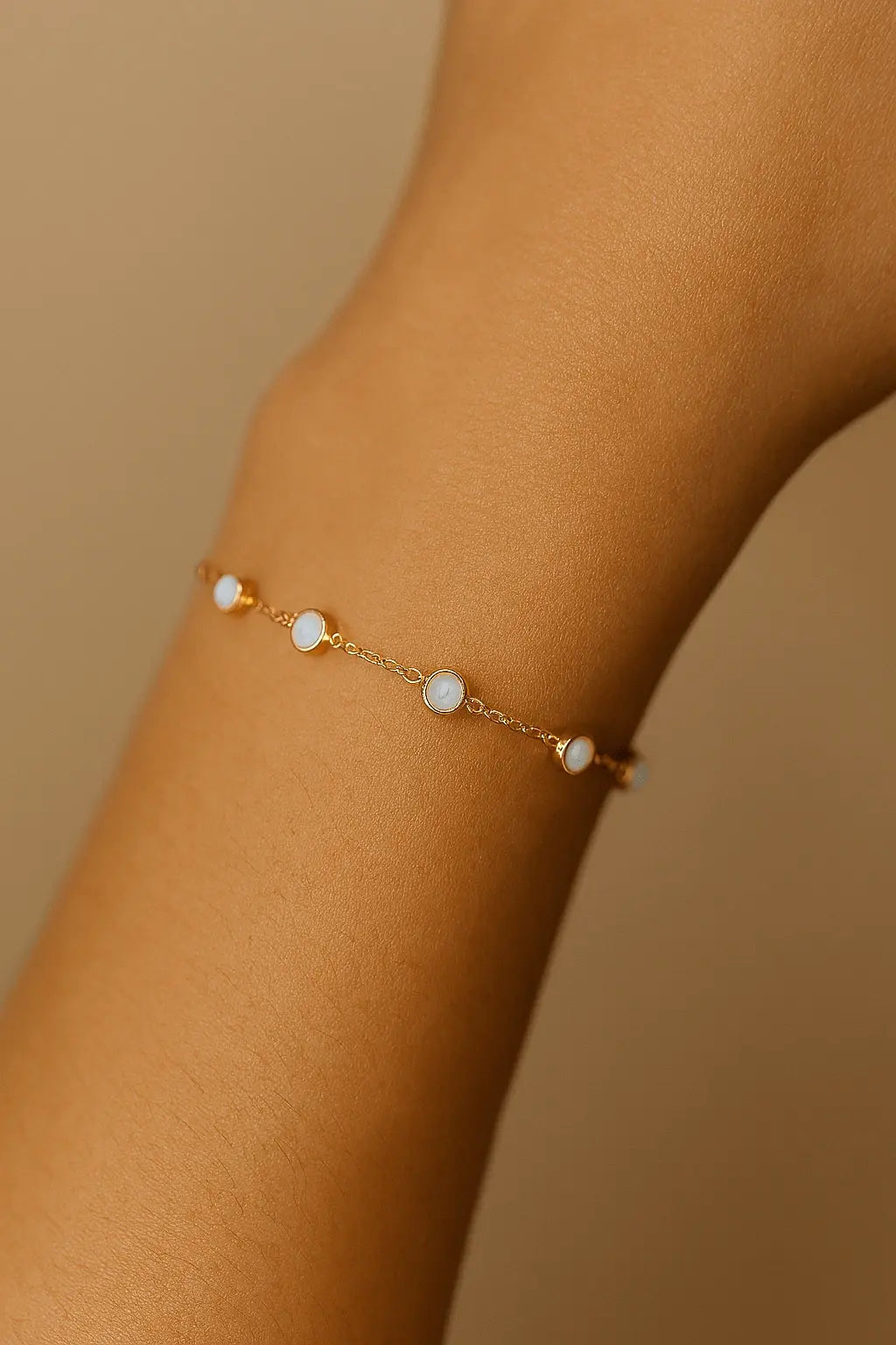 Pulso feminino usando pulseira com pedra opalina dourada estilo romântico