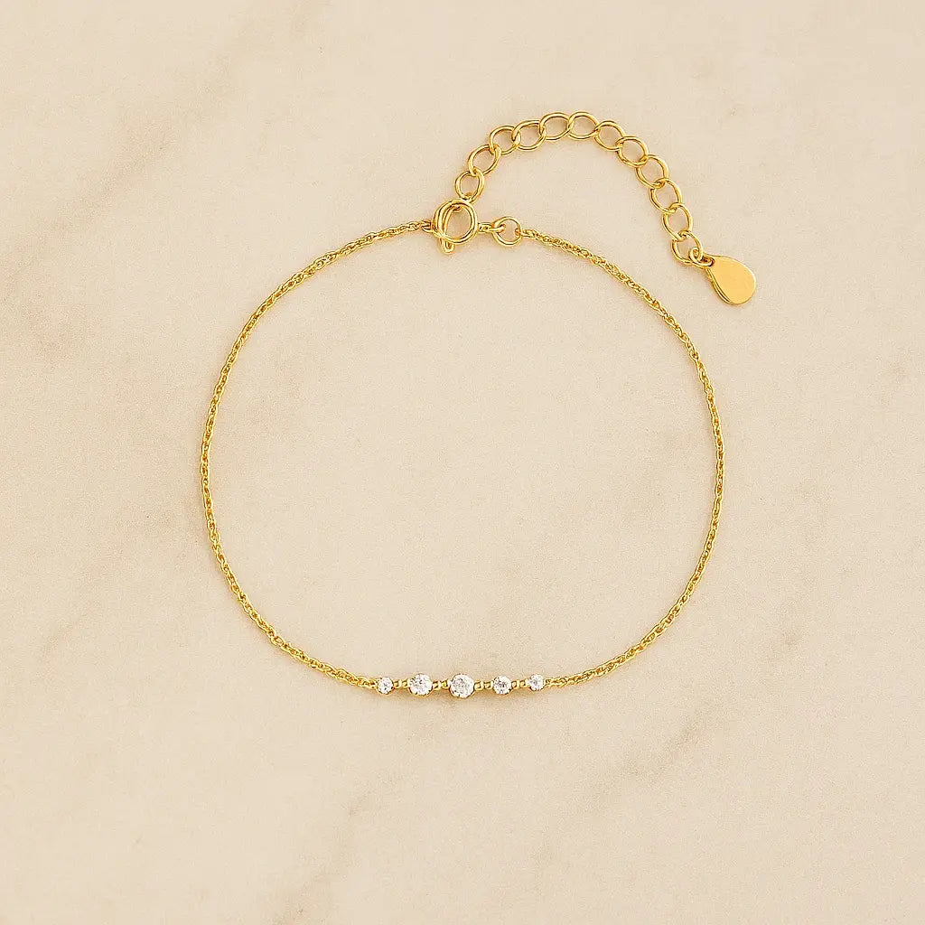 Pulseira minimalista barra dourada cravejada sobre pedra natural clara