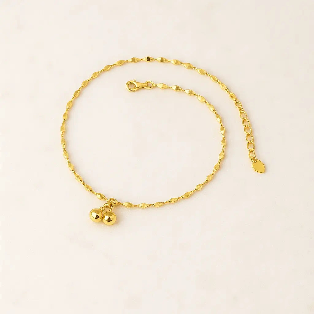 Tornozeleira minimalista pingente dourado sobre pedra natural clara