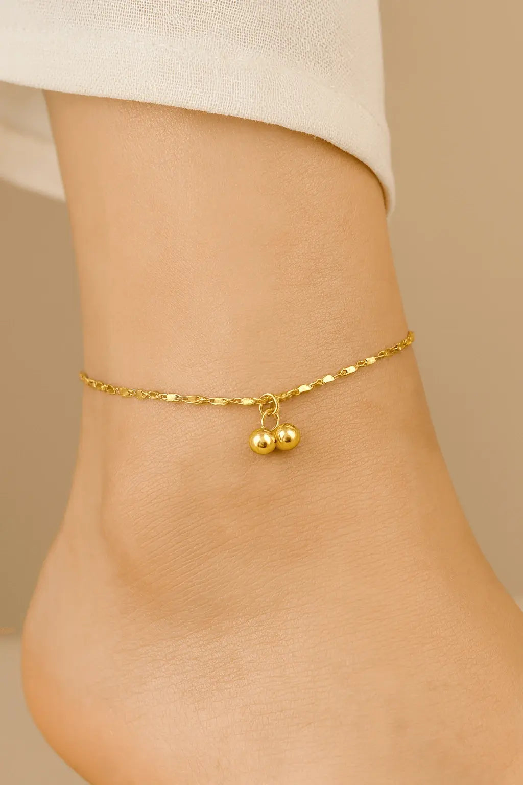 Pés femininos usando tornozeleira com pingente delicado dourado estilo romântico