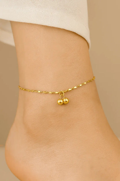 Pés femininos usando tornozeleira com pingente delicado dourado estilo romântico