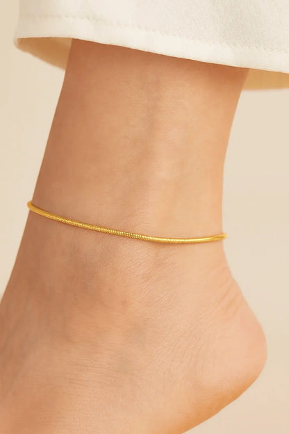 Pés femininos usando tornozeleira malha snake bone dourada estilo moderno