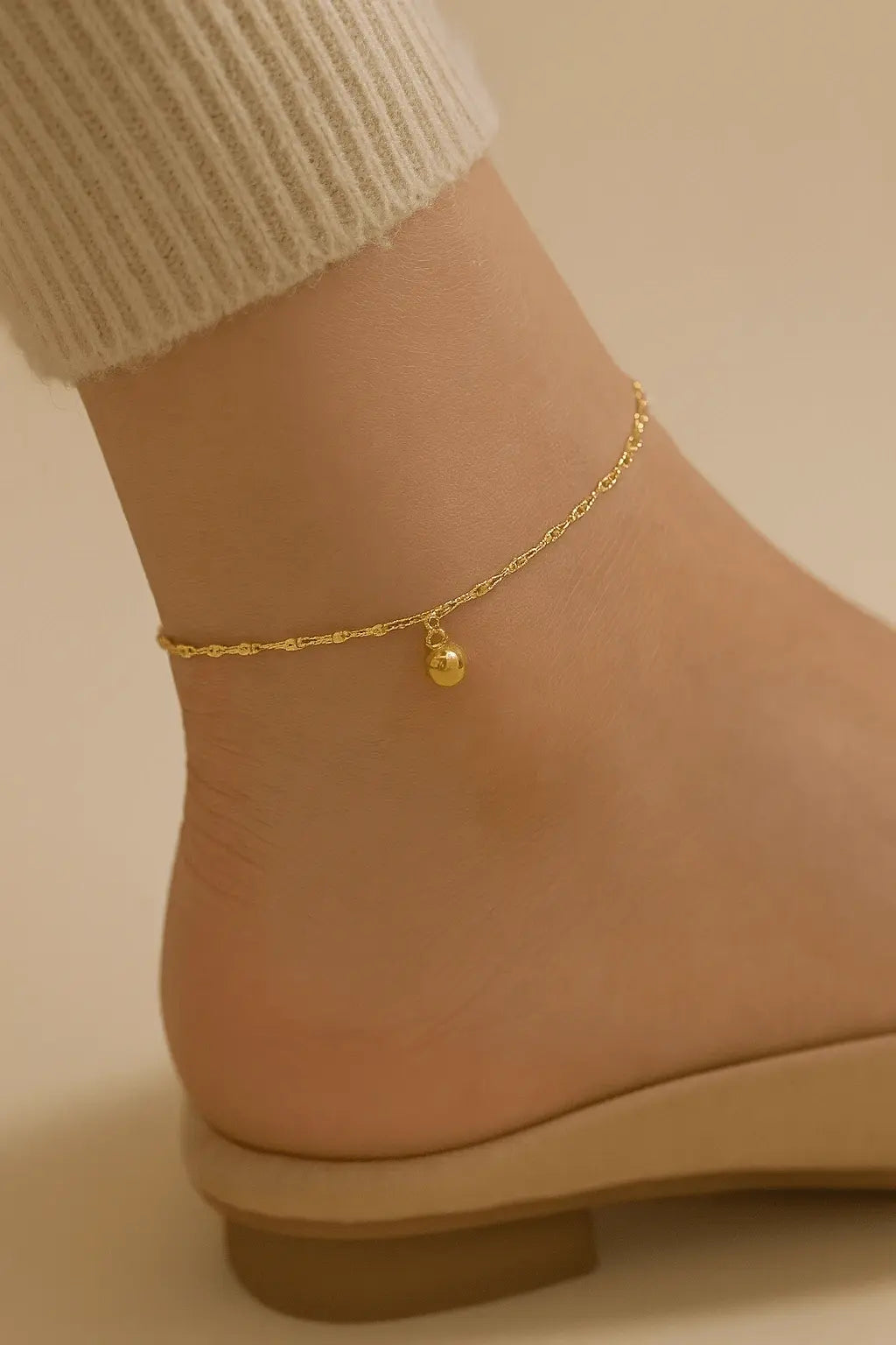 Pés femininos usando tornozeleira de esferas dourada estilo verão elegante